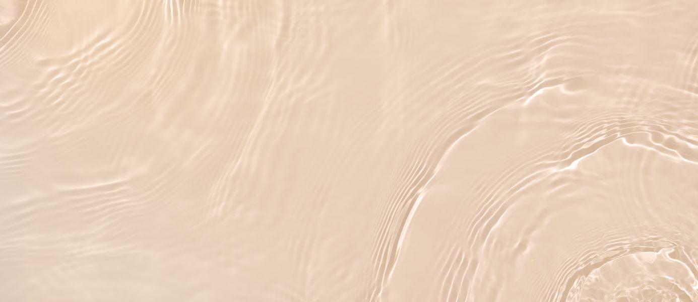 Abstract-summer-banner-background-Transparent-beige-clear-water-surface-texture-with-ripples-and-splashes.Water-waves-in-sunlight